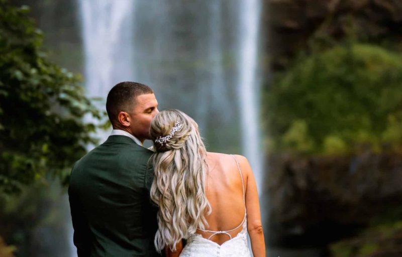 Bride and groom posing in front of Toccoa Falls waterfall