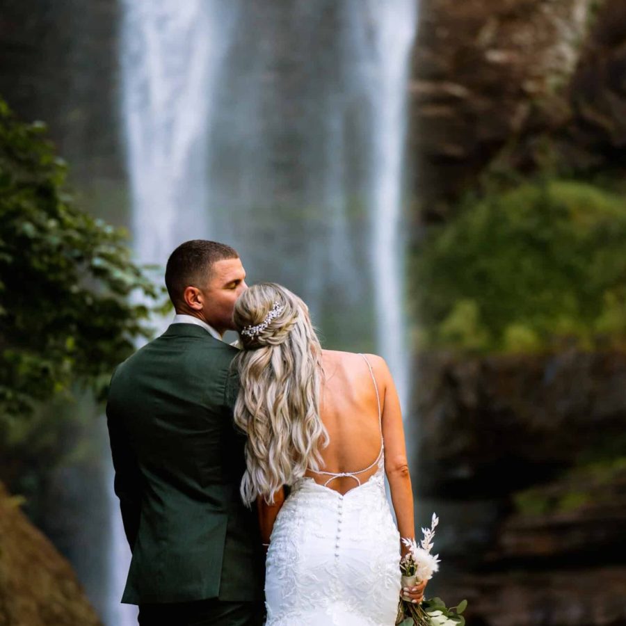 Bride and groom posing in front of Toccoa Falls waterfall